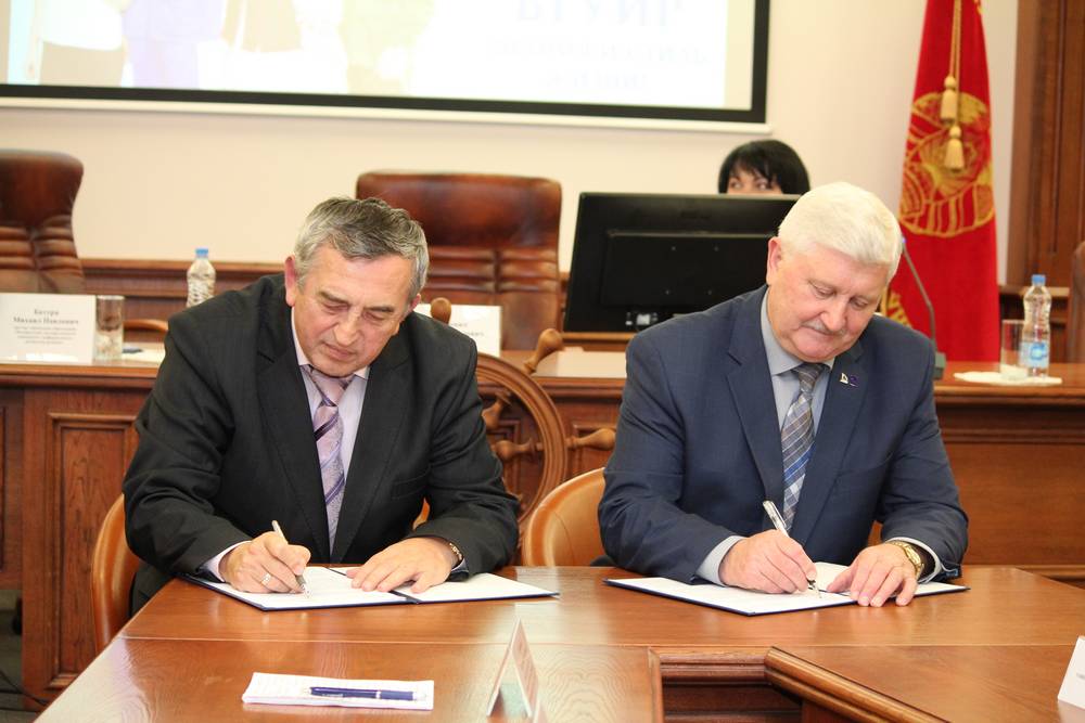 Владимир Сероштан (слева) и Михаил Батура подписывают программу совместного сотрудничества БГУИР и ДОСААФ